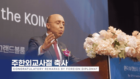 실내 행사장에서 단상에 선 인물을 촬영한 장면
