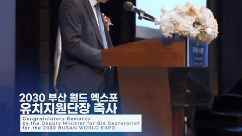 연단에서 인물이 축사를 하고 하단에 순서 자막이 붙은 장면