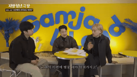 노란 벽 카페 테이블에 세 사람이 둘러앉아 의견을 주고받는 웹예능 장면