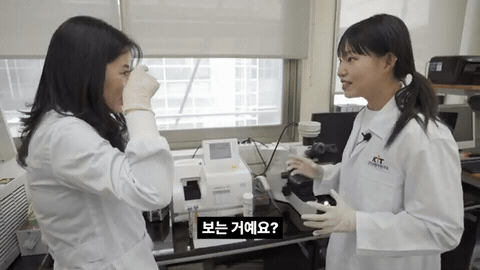 흰 가운을 입은 두 사람이 현미경과 분석 장비 앞에서 마주 서서 이야기하고, 아래에 「정확하게 몇 개 있는지!」 자막이 뜨는 장면