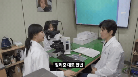 연구실 책상에 앉은 흰 가운 차림 두 사람이 현미경 옆에서 대화하고, 아래에 「배운 대로 한번 해보겠습니다!」 자막이 뜨는 장면