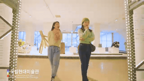미술관 수장고 선반 사이를 두 사람이 웃으며 지나가는 장면